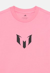 Rosa bomull t-skjorte med rund hals og korte ermer, med en fremtredende svart logo i sentrum. Glatt tekstur.