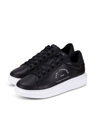 Zapatillas bajas de cuero negro con suelas blancas, cordones negros y texto "Karl Lagerfeld Paris 21 Rue St-Guillaume" en los laterales.