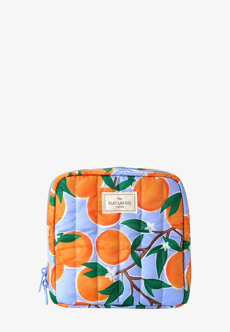 Pequeño bolso acolchado con cremallera, con un patrón de frutas naranjas y hojas verdes sobre un fondo azul claro, etiquetado como "The Flat Lay Co."