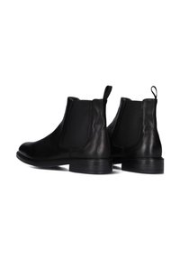 Zwarte leren Chelsea boots met elastische zijkanten, ronde neus, trekhaak en lage blokhak; gladde textuur en eenvoudig ontwerp.