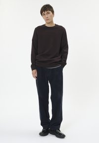 Dark brown sweatshirt with a relaxed fit, navy corduroy trousers, and black shoes. Smooth fabric, crew neckline, and subtle texture.