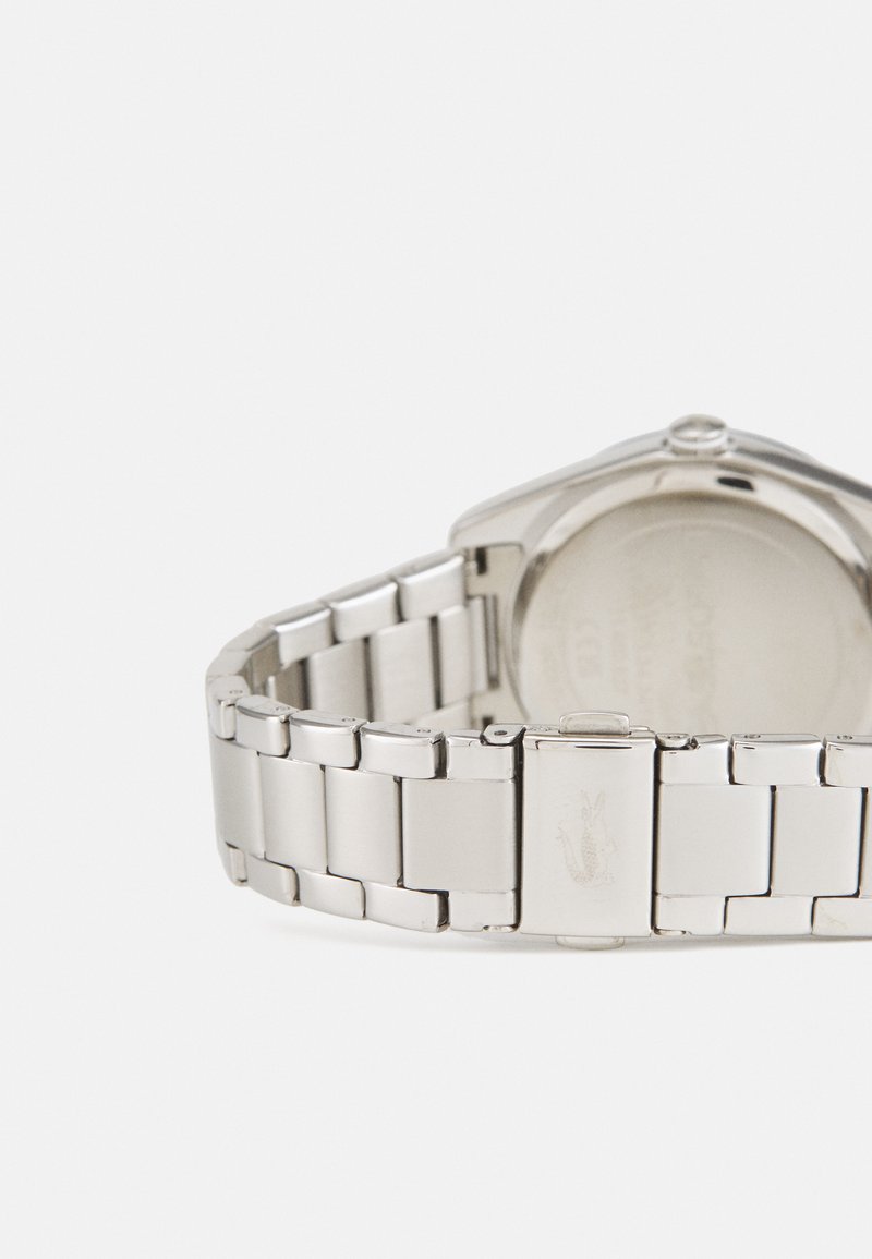 Montre en acier inoxydable argenté avec bracelet à maillons. Boîtier rond aux bords lisses, doté d'un fermoir simple et d'un logo gravé.