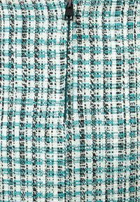 Gewebter Stoff in Hellblau, Schwarz und Weiß mit kariertem Muster und strukturierter Oberfläche; verfügt über einen Reißverschluss zum Verschließen.