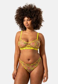 Genomskinlig, blommönstrad lingerie set i ljusrosa och neongul med justerbara band och blommiga detaljer på tyget.