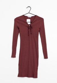 Langsleeve, geribbelde jurk in diep bordeaux, met een V-hals en lace-up detail met strikjes. Materiaal lijkt zacht, met een aansluitend ontwerp.