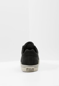 Svarta mockasneakers med rund tå, vit gummi-sula, vadderad krage och "POLO"-logotyp baktill. Minimalistisk design.