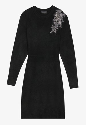 Black knit dress with a round neckline and long sleeves. Features textured ribbing at the waist and a floral embroidery detail on one shoulder.
