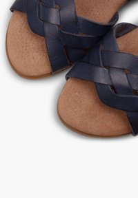 Laivaston siniset punottu nahkaa sandaalit, joissa on tasapohja, tummanruskea teksturoitu jalkapohja ja sileä vaaleanruskea pohja, joka tarjoaa vetopitoa.