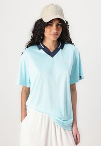 Lys blå kortermet polo skjorte med marineblå krage og vertikale striper. Har brodert logo på brystet. Casual passform.