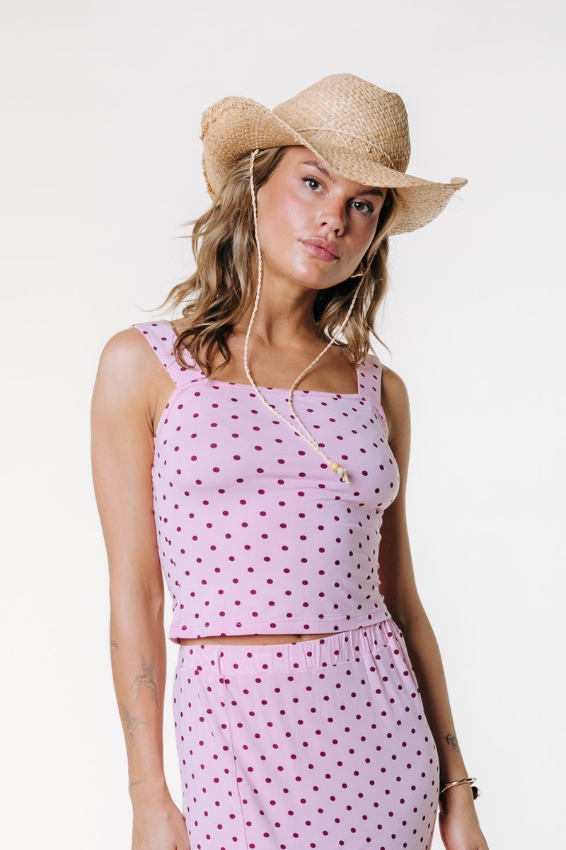 Ροζ crop top με πουά σχέδιο από μαλακό ύφασμα, με τετράγωνο ντεκολτέ και λεπτές τιράντες, σε συνδυασμό με φούστα με ελαστική μέση και ψάθινο καπέλο.