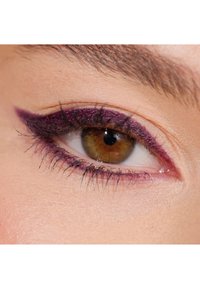 Primo piano di un occhio con iride marrone, ciglia nere e eyeliner viola scuro che si estende verso l'esterno, evidenziando la forma della palpebra.
