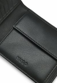 Zwarte leren portemonnee met een getextureerd oppervlak, een kaartsleuf en een geperst logo. De stiknaden zijn zichtbaar langs de randen.
