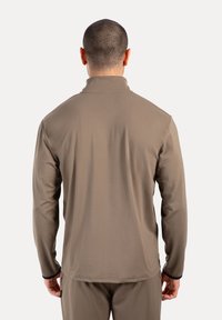 Langärmliges, braunes Sportoberteil mit hohem Kragen. Glatte Textur, gerader Schnitt und schwarze Akzente an den Bündchen und dem Saum. Minimalistisches Design.