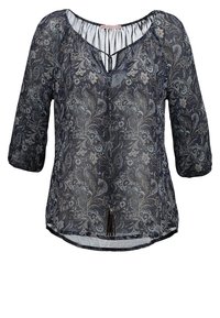 Blouse noire semi-transparente avec motif floral cachemire blanc, manches trois-quarts, encolure goutte et lien à pompons à l'avant.
