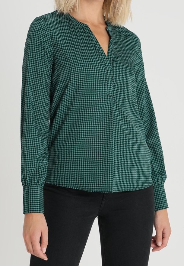 Grön blus med rutigt mönster, långa ärmar, V-ringning och samlad manschettdetalj. Lättviktsmaterial med en mjuk textur.