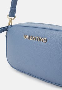 Blue textured leather handbag with a gold "Valentino" logo. Features a detachable shoulder strap and smooth edges.