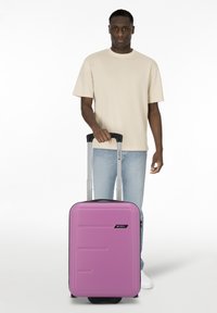 Maleta de carcasa dura en un vibrante color rosa, con paneles texturizados y un asa retráctil. Diseño ligero con ruedas que se deslizan suavemente.