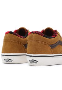 Zapatillas de ante marrón con un forro de cuadros rojos y negros, suela de goma blanca y un logo negro de Vans en la parte trasera. Diseño de perfil bajo.