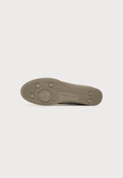 Semelle d’une chaussure avec motifs circulaires et rainures en zigzag, couleur beige, taille 47 marquée, sur fond blanc.