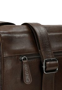 Bruine leren schoudertas met een gestructureerd ontwerp, voorzien van een ritsvak, zilveren accenten en een verstelbare schouderband.