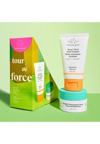 Drunk Elephant skincare set featuring a white jelly cleanser tube with orange cap and a turquoise jar with white base, both in a vibrant green box.
