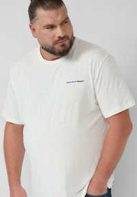 Witte katoenen t-shirt met een ronde hals en korte mouwen, met een klein "Subscribe to Nature®" logo in donkerblauw op de linkerkant van de borst.