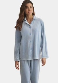 Ensemble de pyjama en peluche bleu clair comprenant un haut à col et à boutons avec des manches longues, assorti à un pantalon, le tout avec une texture douce.