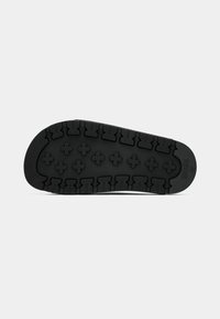 Semelle de chaussure en caoutchouc noir avec un motif de profondeur et logo BOSS, taille 37 visible sur la zone du talon sur un fond uni.