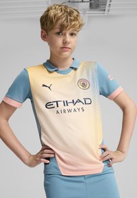 Svetlomodrý a pastelovožltý futbalový dres s golierom, s logom ETIHAD AIRWAYS a erbom Manchester City. Krátke ružové rukávy.