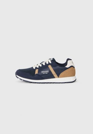 Baskets Jack & Jones bleu marine et beige avec lacets et semelle blanche, vue de côté sur fond gris clair uni.