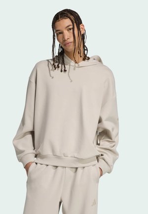 Sweatshirt capuche beige clair en matériau doux, avec une coupe décontractée, des poignets côtelés et un accent logo minimaliste sur l'ourlet.
