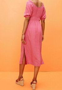 Roze linnen jurk met puffmouwen en een getailleerde taille, met een zijsplit en een ontspannen pasvorm. Gemaakt met bruin wedge-sandalen.