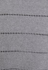 Tissu tricoté gris avec des lignes horizontales de petits trous, présentant une texture douce et des mailles uniformes dans l'ensemble.