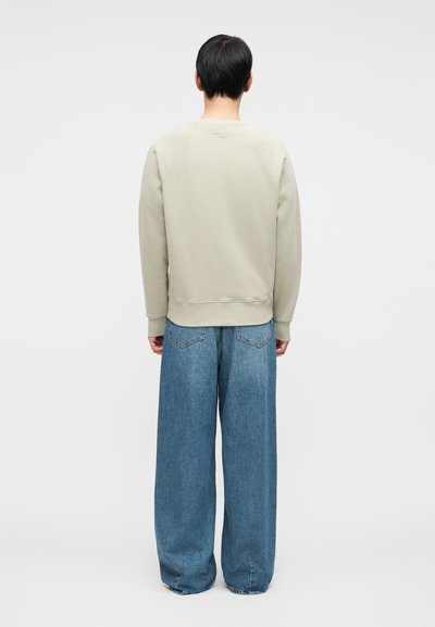 Γκρι φούτερ με ραγκλάν μανίκια, στρογγυλή λαιμόκοψη και ριμπ μανσέτες. Συνδυασμένο με άνετο στυλ μπλε τζιν τζιν με πίσω τσέπες.