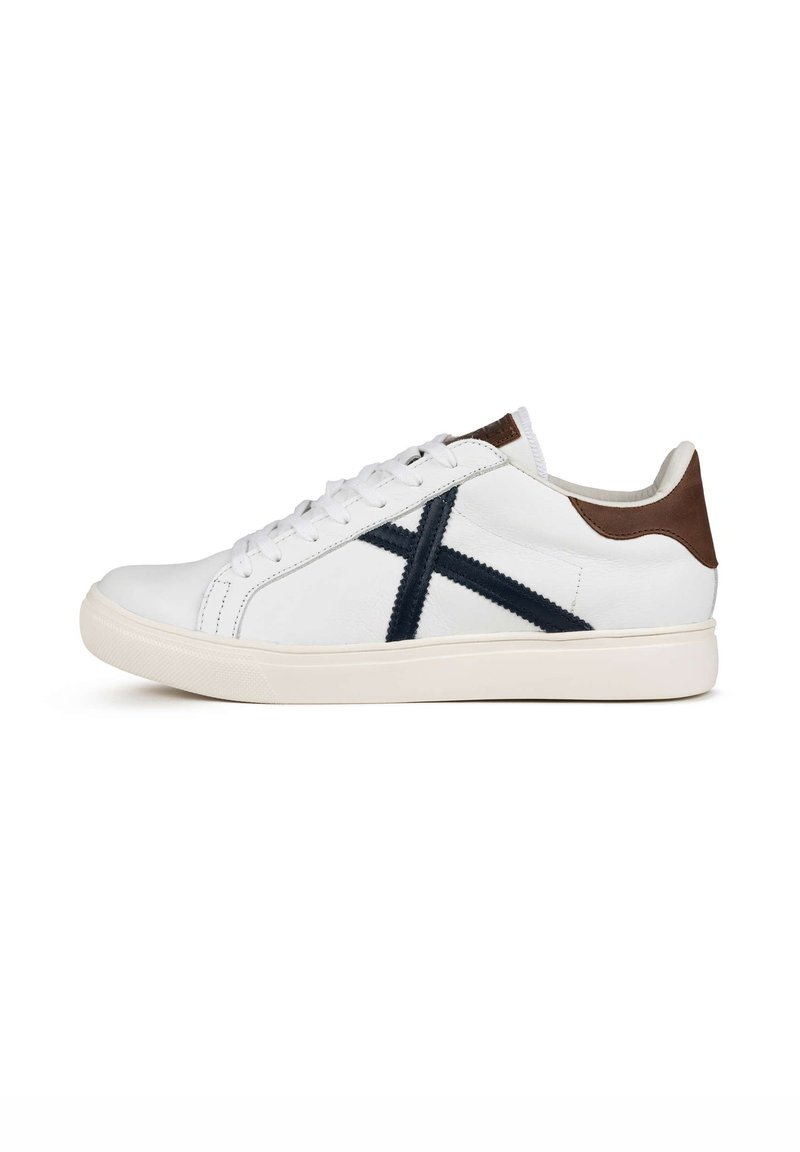 Sneaker in pelle bianca con strisce di accentuazione blu navy. Presenta un inserto in pelle marrone sul tallone, punta tonda, chiusura con lacci e suola in gomma testurizzata.