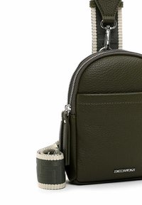 Mørkegrøn læder crossbody taske med struktureret overflade, sølv lynlås og justerbar rem med mønstret vævning. Mærket tag er synligt.