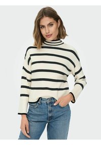 Wit en zwart gestreepte trui met een hoge kraag, geribbelde textuur en een ontspannen pasvorm. Gepaarde met hooggetailleerde blauwe jeans.