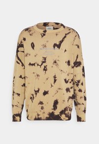 Jersey beige con patrones de estampado anudado en negro, puños y dobladillo acanalados, y un cuello redondo. En la parte delantera presenta un logo de texto en azul claro. Textura suave.