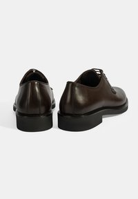 Bruine leren schoenen met een ronde neus en vetersluiting. Beschikken over een gestructureerd bovenwerk, een gladde afwerking en een zwarte rubberen zool.