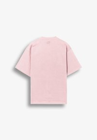 T-shirt rose clair à manches courtes vu de dos avec une petite lettre brodée "B" près de l'encolure sur fond blanc.