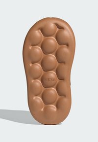 Semelle extérieure brune et texturée d'une sneaker avec des nodules arrondis pour une meilleure adhérence. Présente le logo "adidas" en relief près du talon.