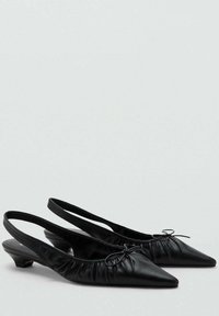 Mustat slingback-kengät, joissa on terävä varvaskärki ja ne on valmistettu sileästä nahasta. Kengissä on kerättyä pintaa sekä kapeita nauhoja, joissa on pienet rusettiyksityiskohdat.
