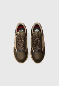 Scarpe da ginnastica marroni e beige con un mix di pelle e tessuto testurizzato. Presentano lacci rotondi e una soletta nera e rossa. Suola in gomma piatta.