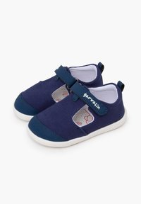 Zapatillas de lona azul marino con cierre de correa, suela de goma blanca y paneles laterales recortados. Presentan detalles con el logo y un forro interior suave.