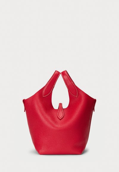 Sac à main en cuir rouge avec une surface texturée, des poignées découpées uniques et des coutures contrastées. Sa forme compacte et simple convient à un usage quotidien.