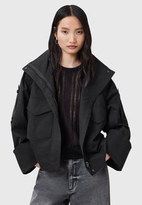 Giacca cropped nera in tessuto opaco e texturizzato. Caratterizzata da rever oversize, tasche anteriori con patta e chiusura a zip.