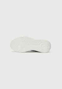 Sole of a sneaker featuring a textured white rubber bottom with circular and wavy patterns, providing traction and durability.