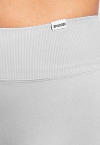Ceinture côtelée grise des leggings avec une étiquette tissée "SMILODOX", texture de tissu lisse et couture soignée.
