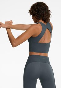Top court gris côtelé à dos nageur, associé à un legging taille haute assorti, mettant en valeur une texture lisse et un matériau élastique.