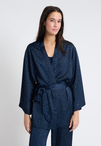 Robe stile kimono di colore navy con motivo foglia verde, maniche lunghe, design avvolgente e cintura abbinata, realizzato in tessuto leggero.